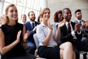 Diverse group of employees smiling and clapping at a presentation