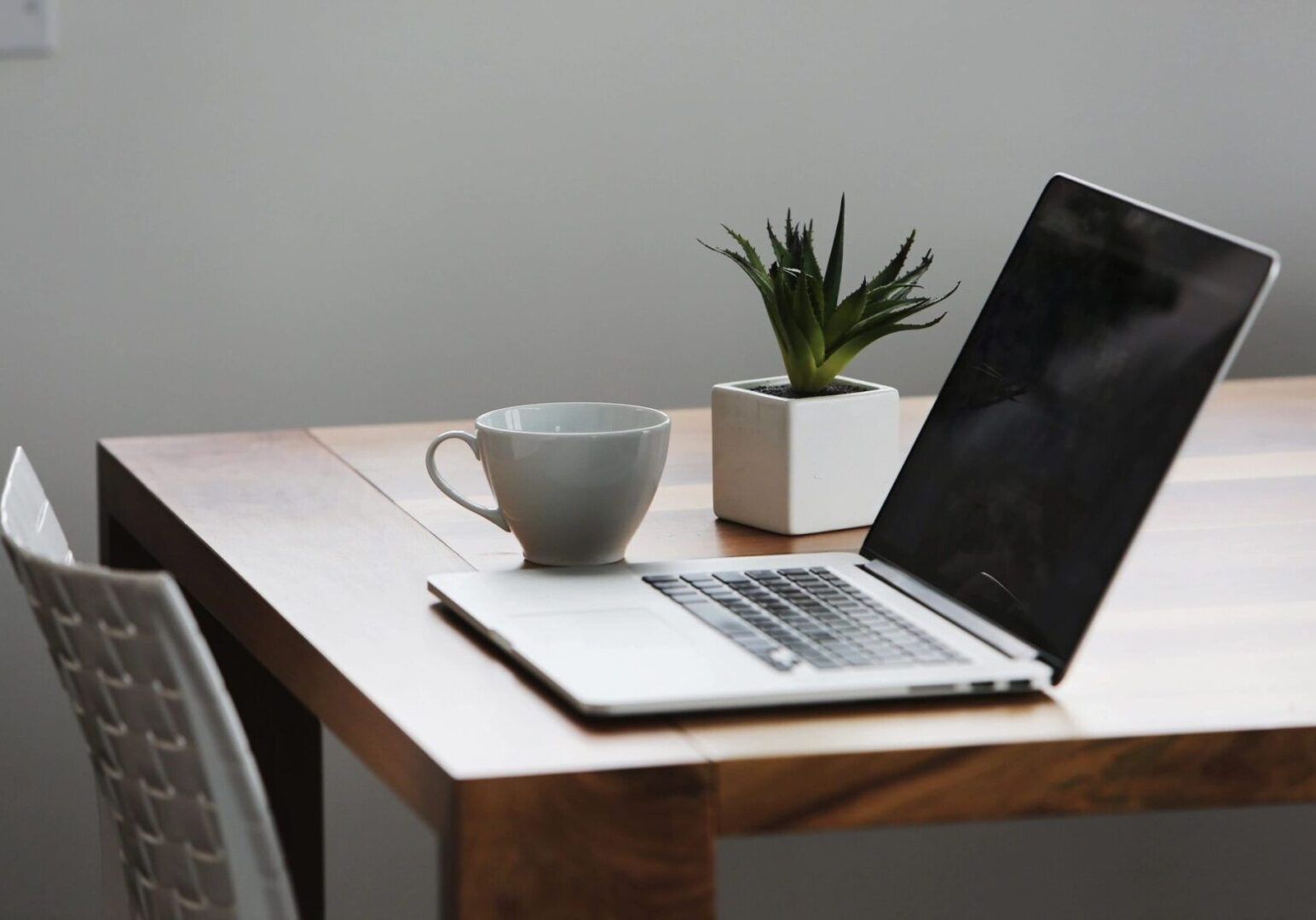 A young professional sitting at a desk with a laptop and notepad, looking focused and prepared, symbolizing thorough research and preparation for a job interview.